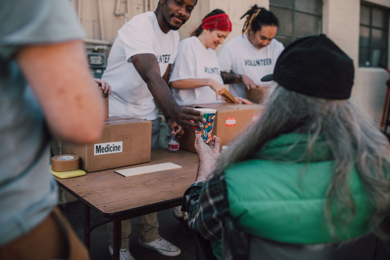 Volunteers welcome community members at an outreach table.