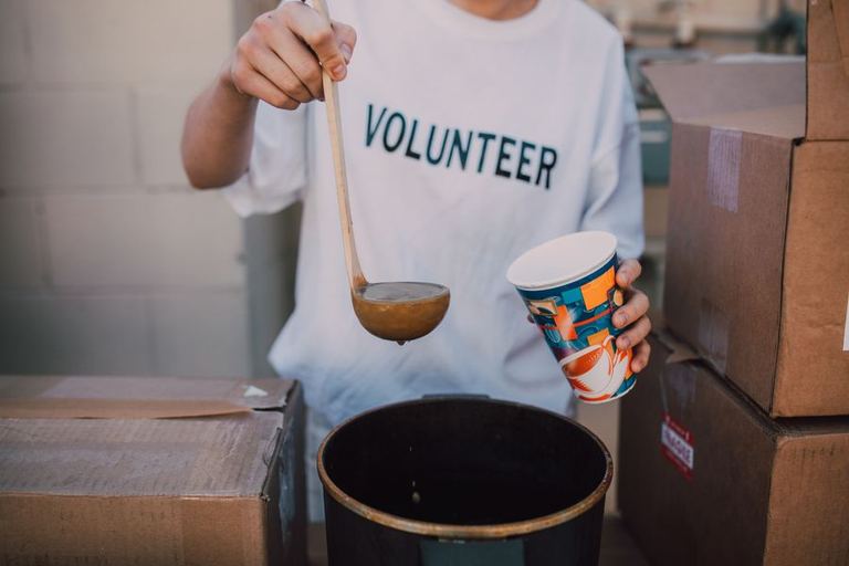 A volunteer serves food from a large pot.
